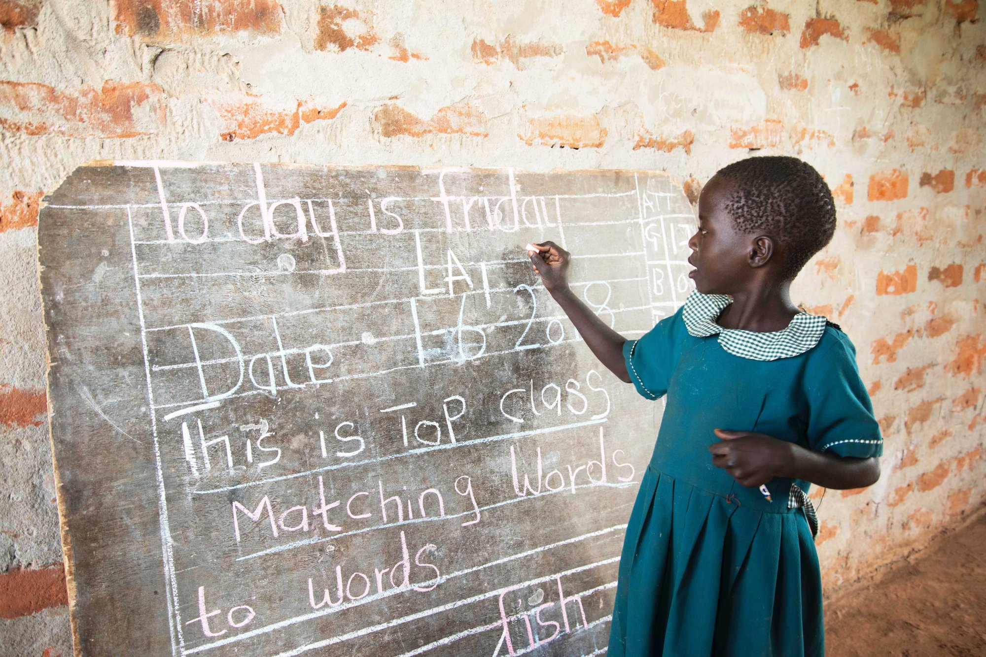 Schoolmeisje in Oeganda schrijft op schoolbord