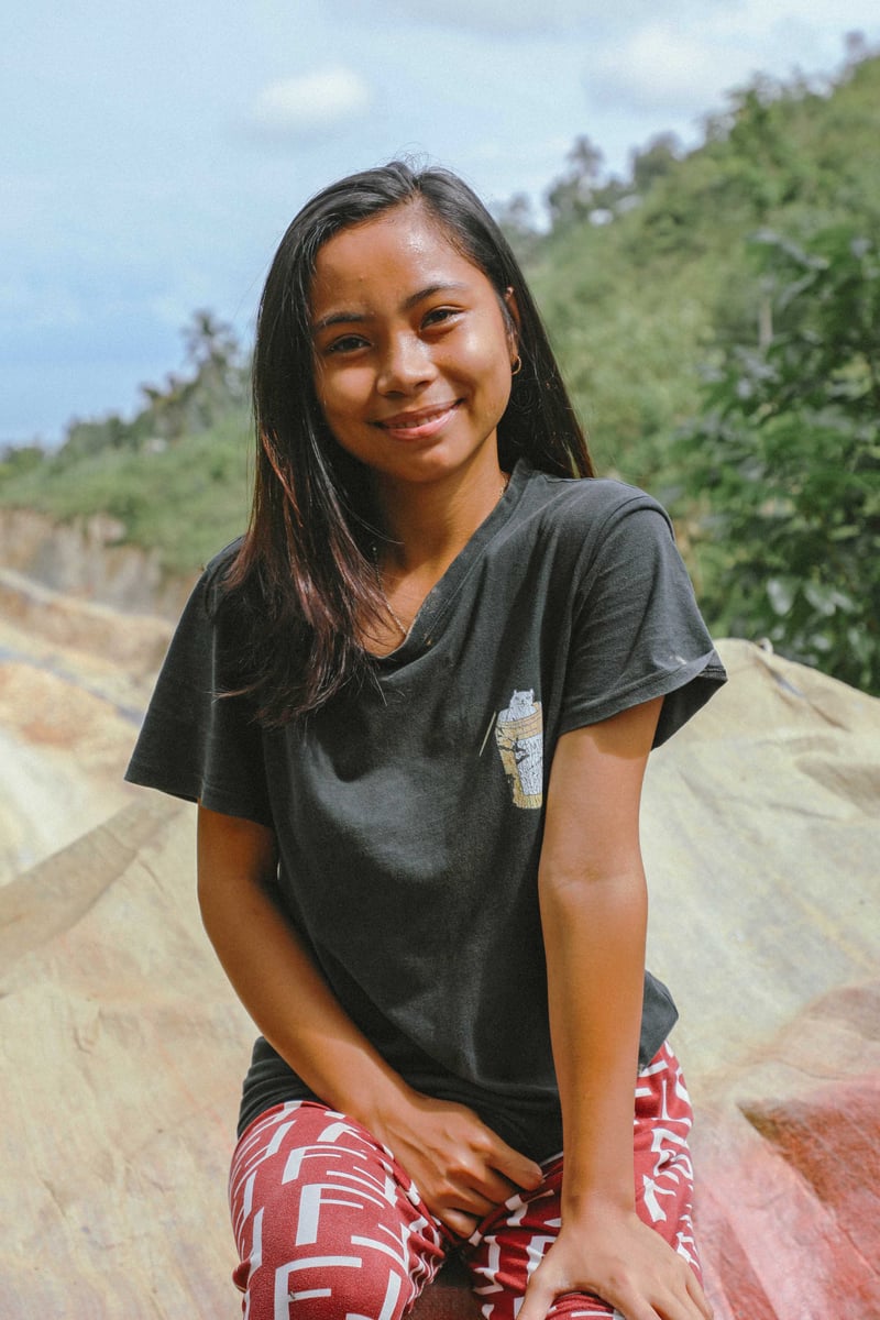 Jeune adolescente de Philippines assise sur un rocher et regardant la caméra.