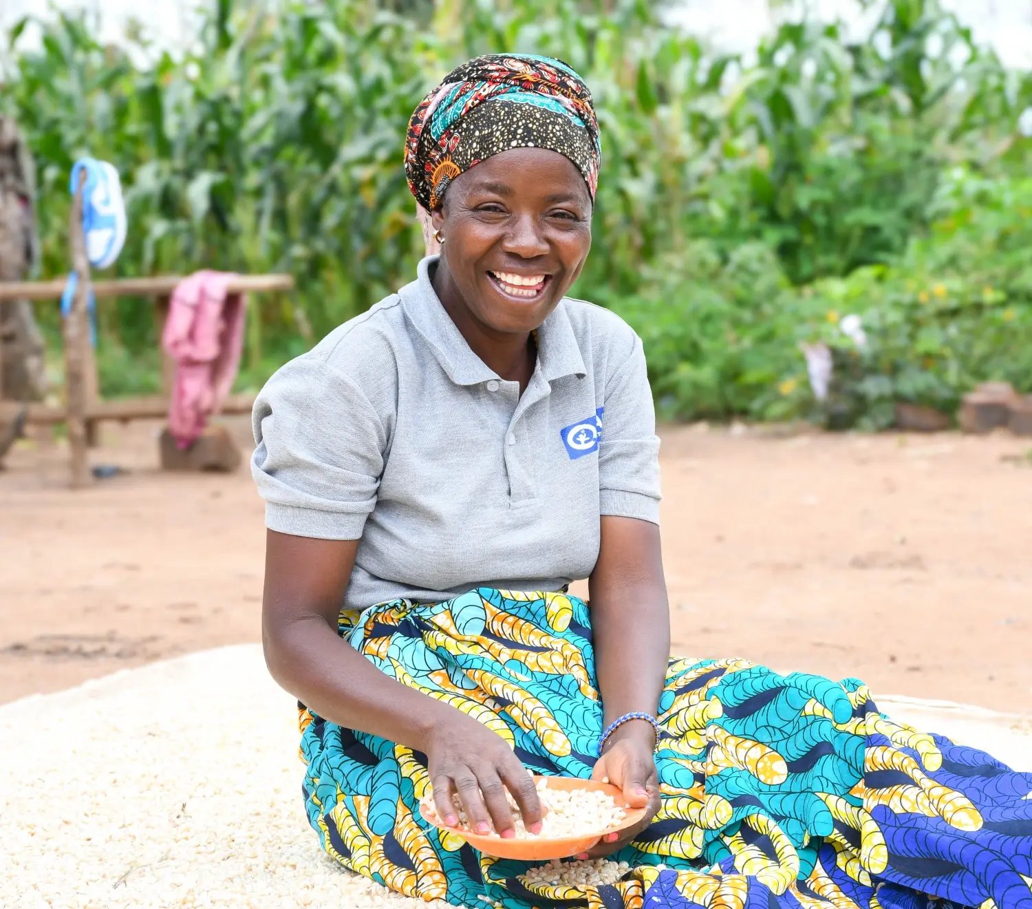 Edwina, 40 jaar, lacht terwijl ze een schaaltje met maïs vasthoudt op haar bedrijf.