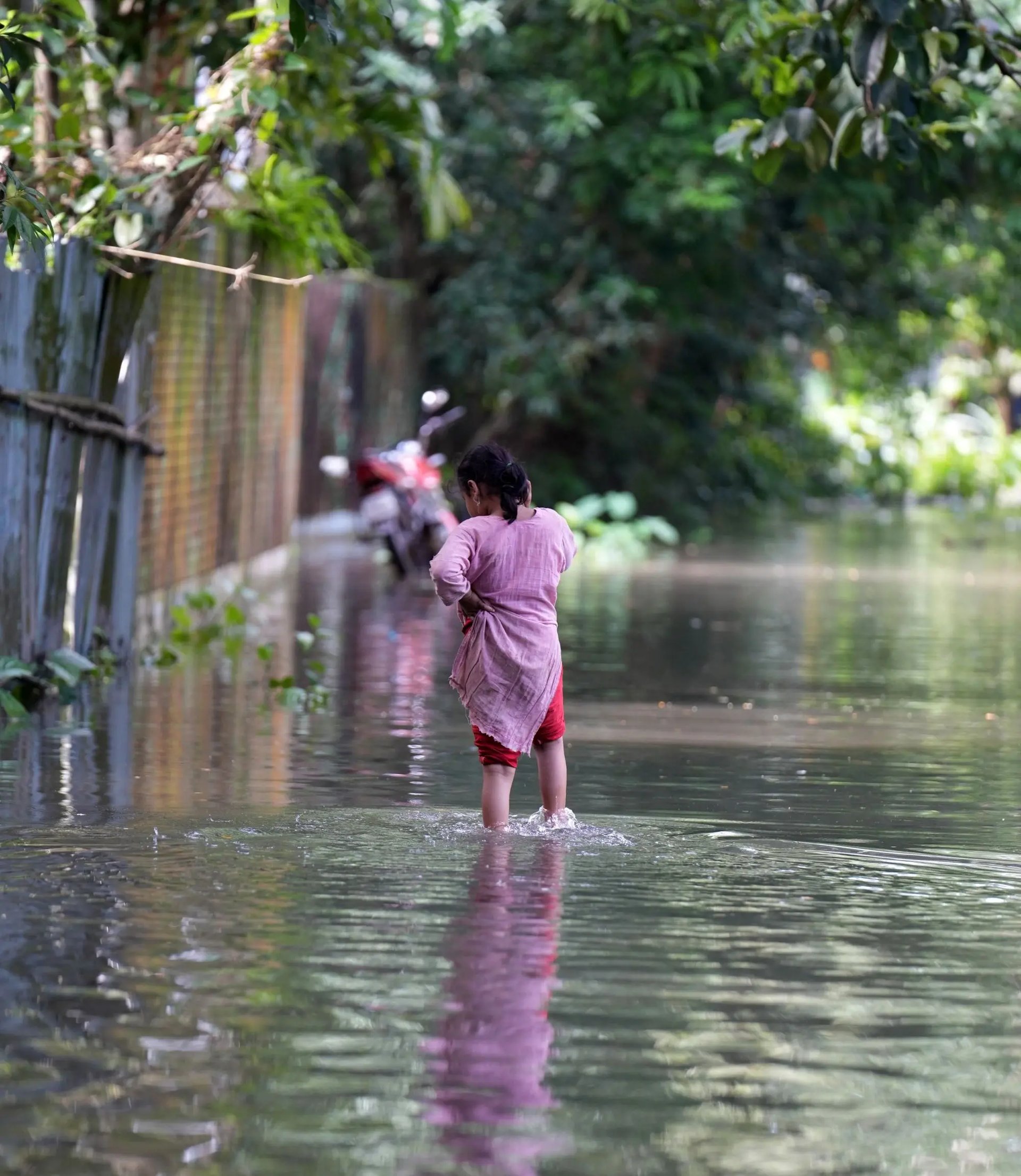 Een jong meisje loopt door het water na zware overstromingen veroorzaakt door uitzonderlijke regenval in Bangladesh.