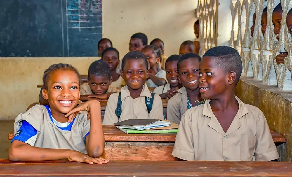 Kinderen volgen lessen in een klaslokaal uitgerust door Plan International in Benin