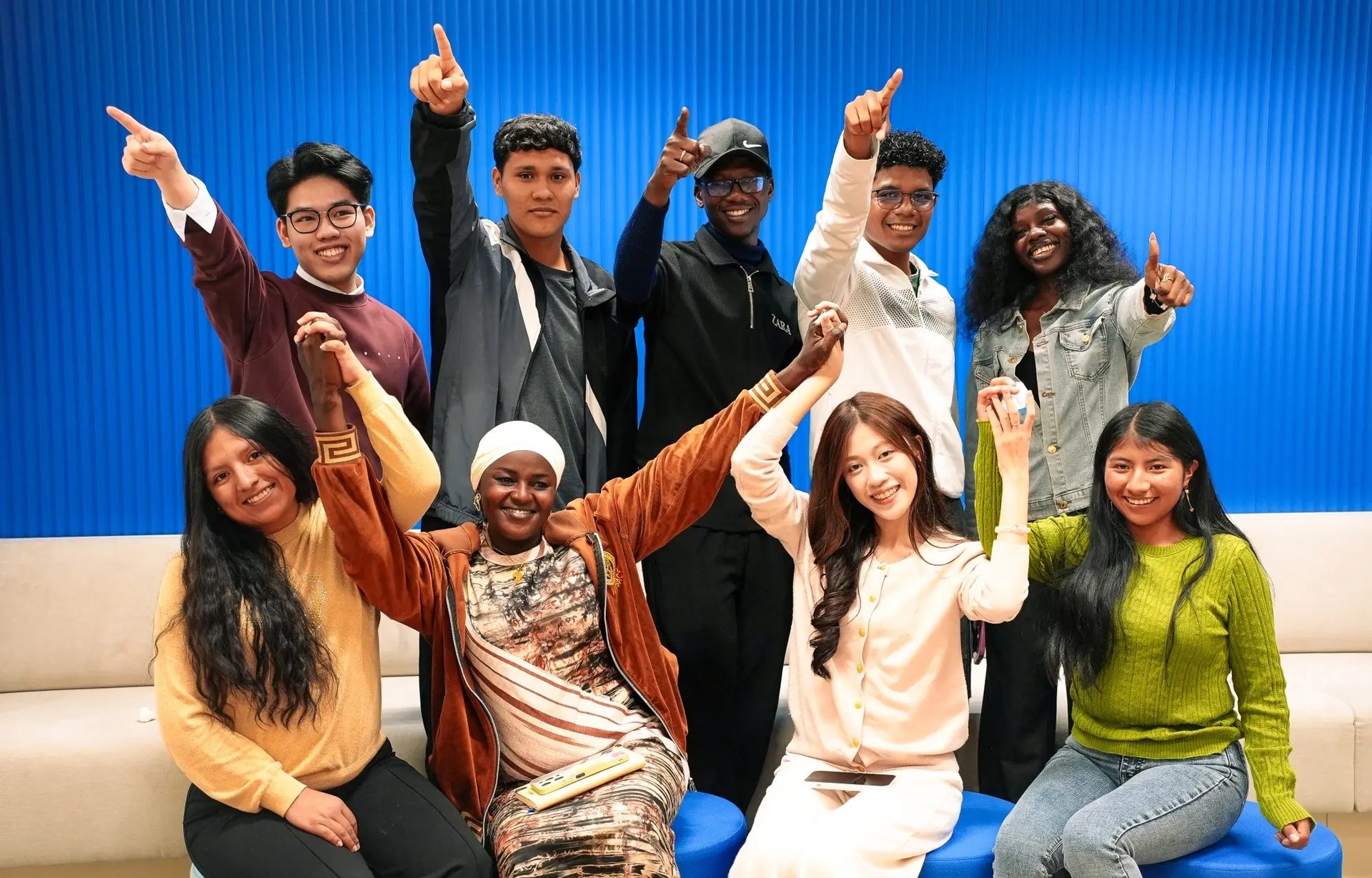 Jonge leiders uit Vietnam, Ecuador, Niger, Senegal, Vietnam en Bolivia poseren trots in de kantoren van Plan International België. 