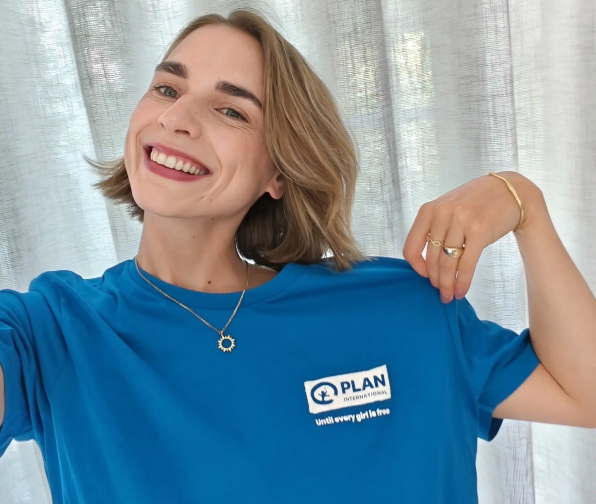 Elisabeth Lucie Baeten, ambassadrice van Plan International België, poseert trots in ons blauwe T-shirt.