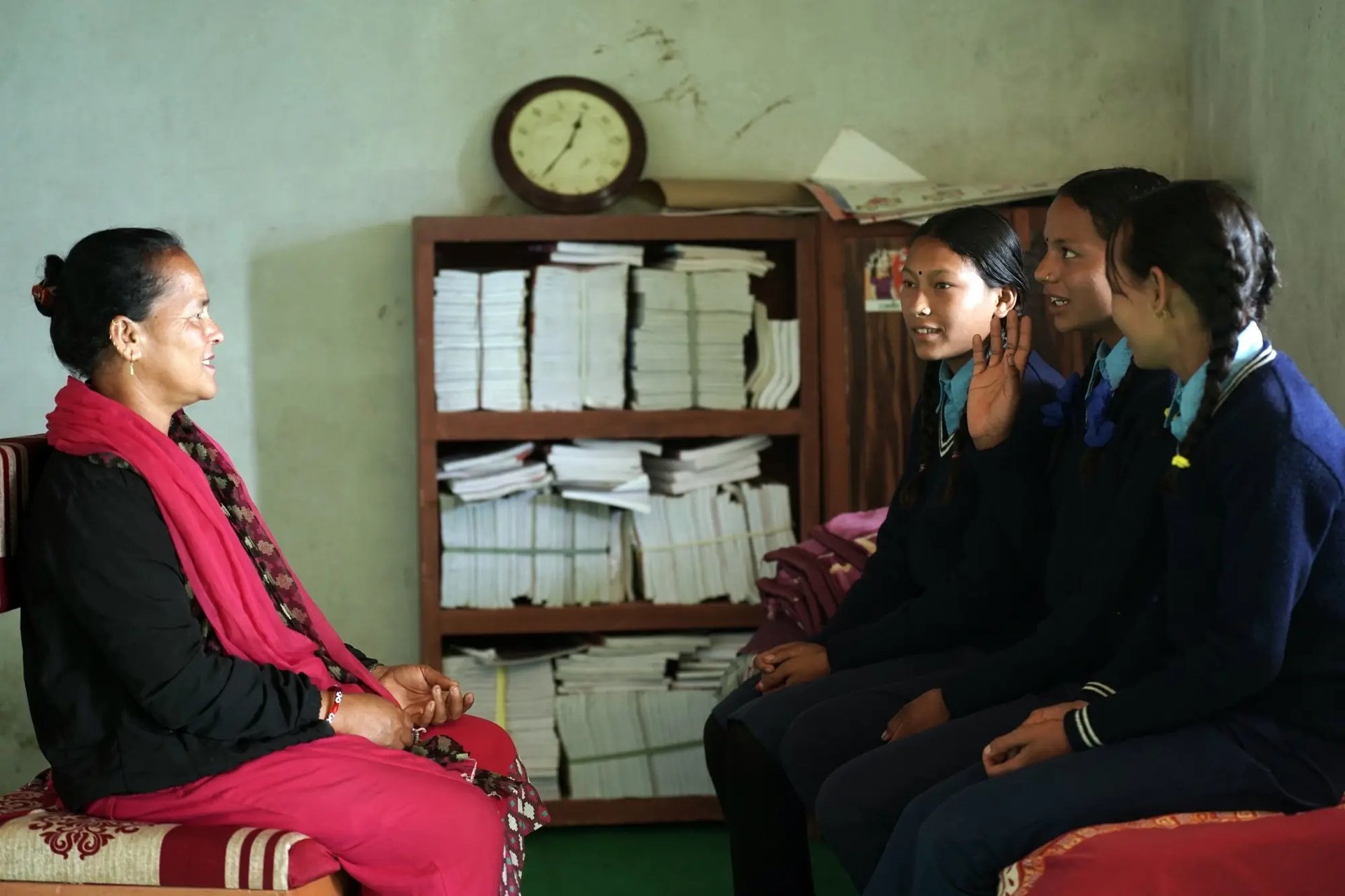 Een leerkracht luistert naar haar leerlingen in Nepal, waar Plan International open gesprekken met meisjes over seksuele en reproductieve gezondheid stimuleert.