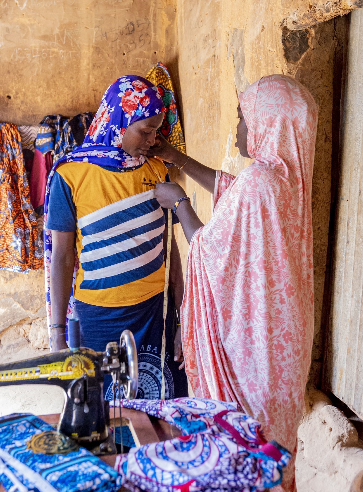 Saratou prend les mesures d’une cliente pour lui coudre une robe. 