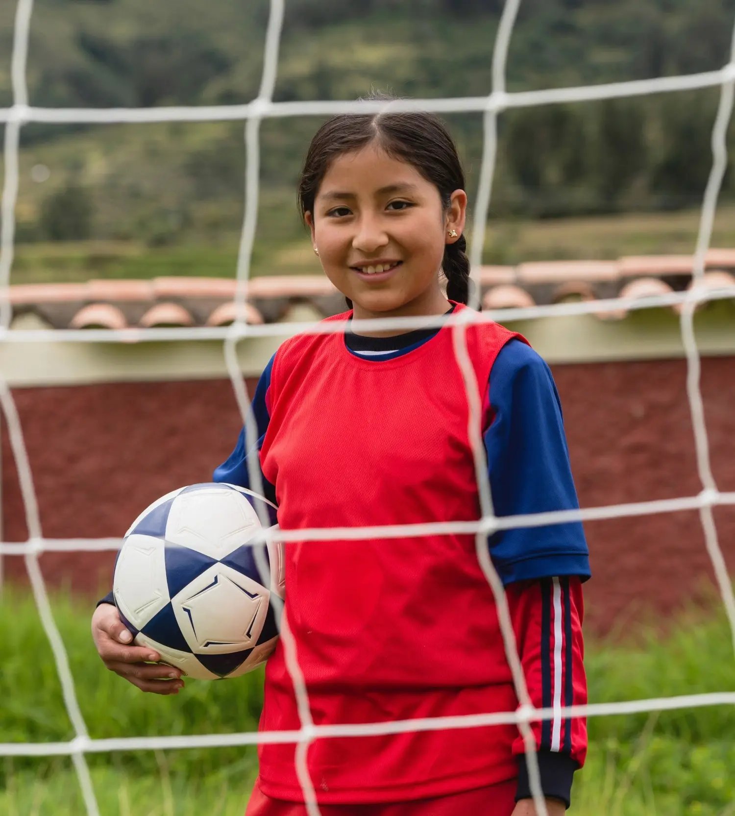 Une fille participant à Change the Game au Pérou se tient fièrement derrière un goal de football.