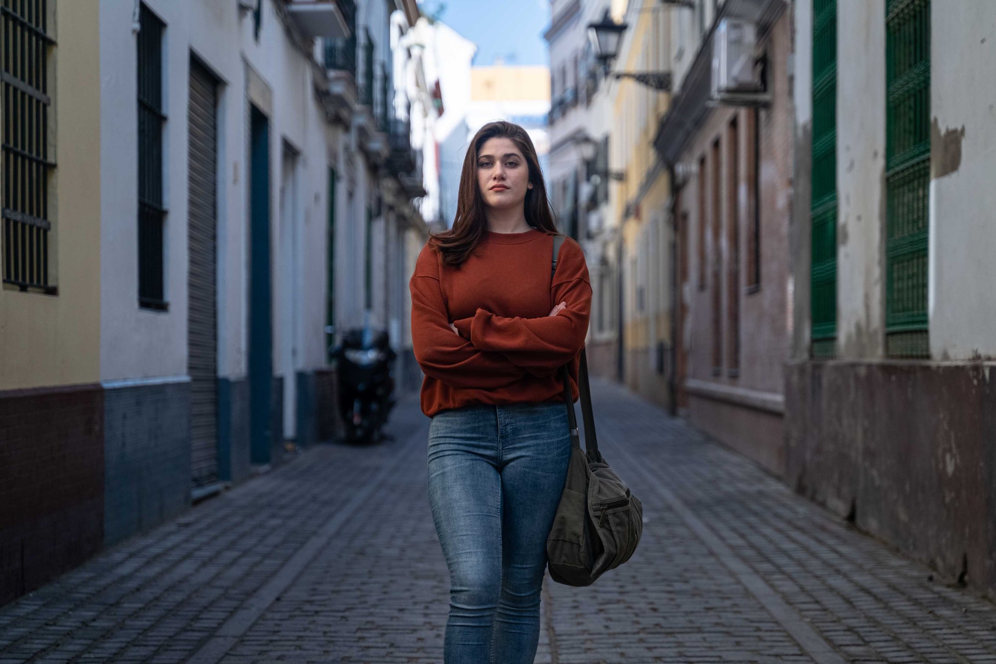 Jeunes femmes dans la rue, bras croisés fait face à la caméra.