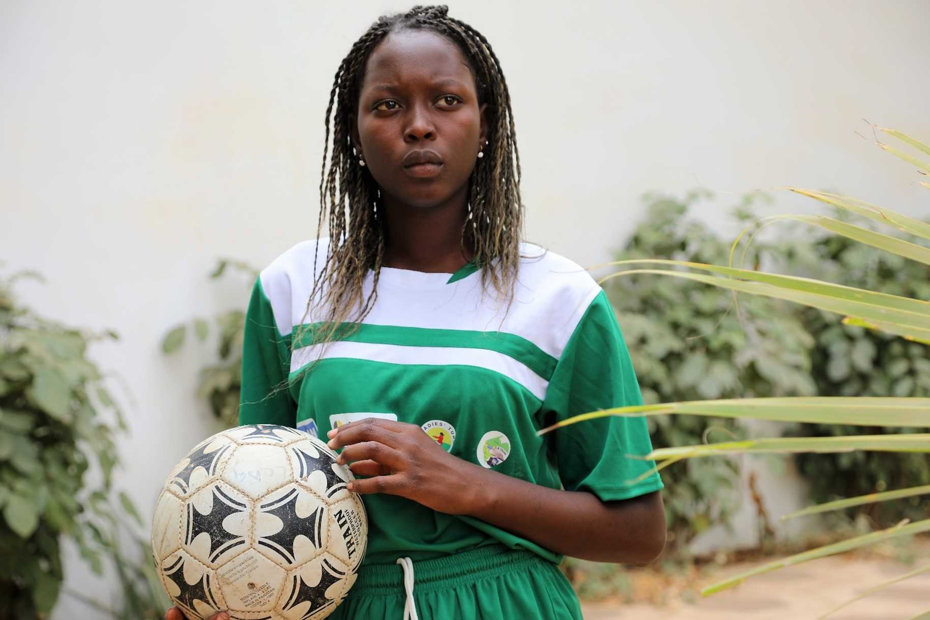 Een Senegalese vrouw met een voetbal in haar handen. 