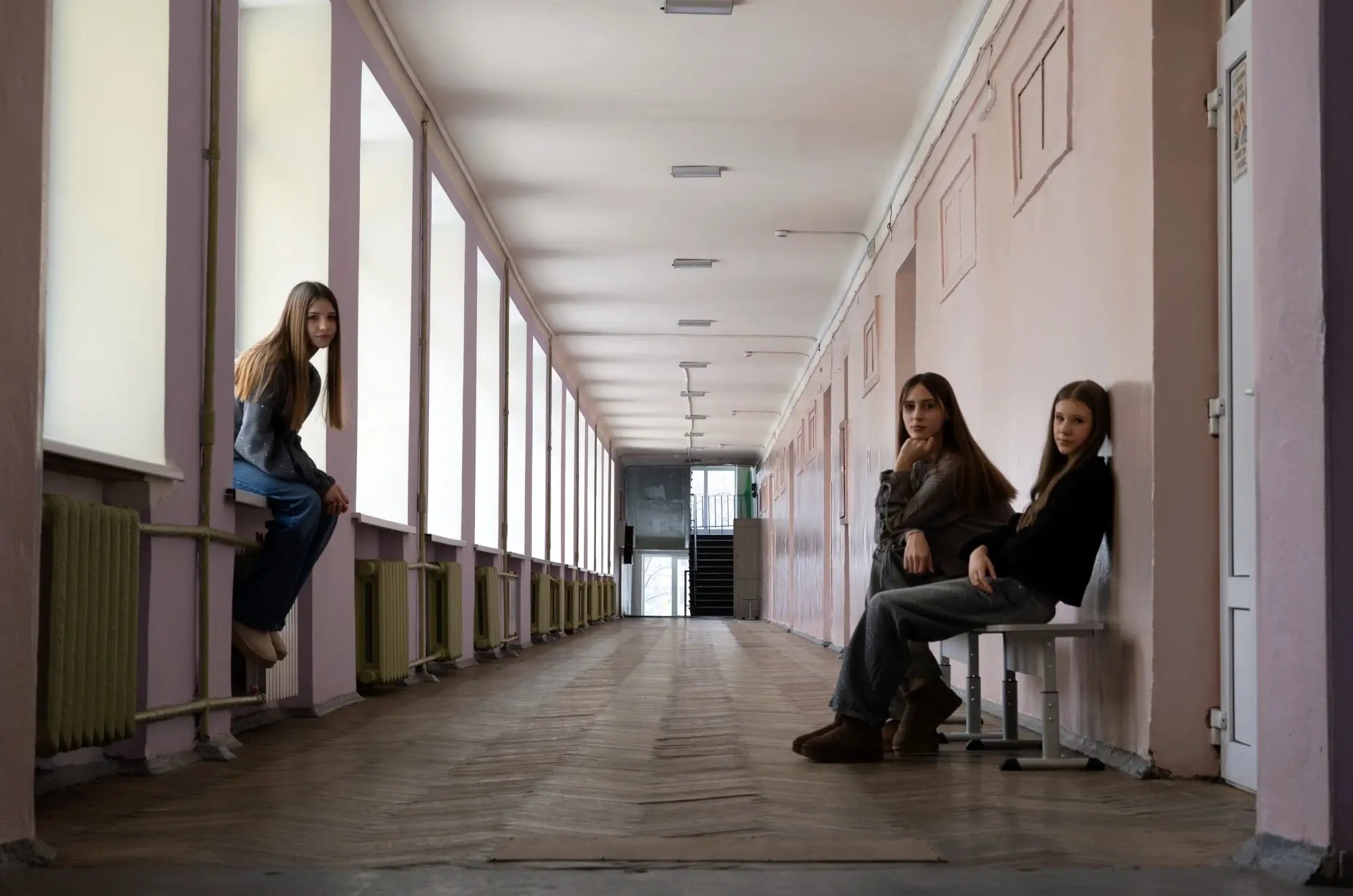 Kateryna, 13 jaar, Kateryna, 14 jaar, en Zoriana, 14 jaar, in de gang van een verlaten school in Oekraïne.