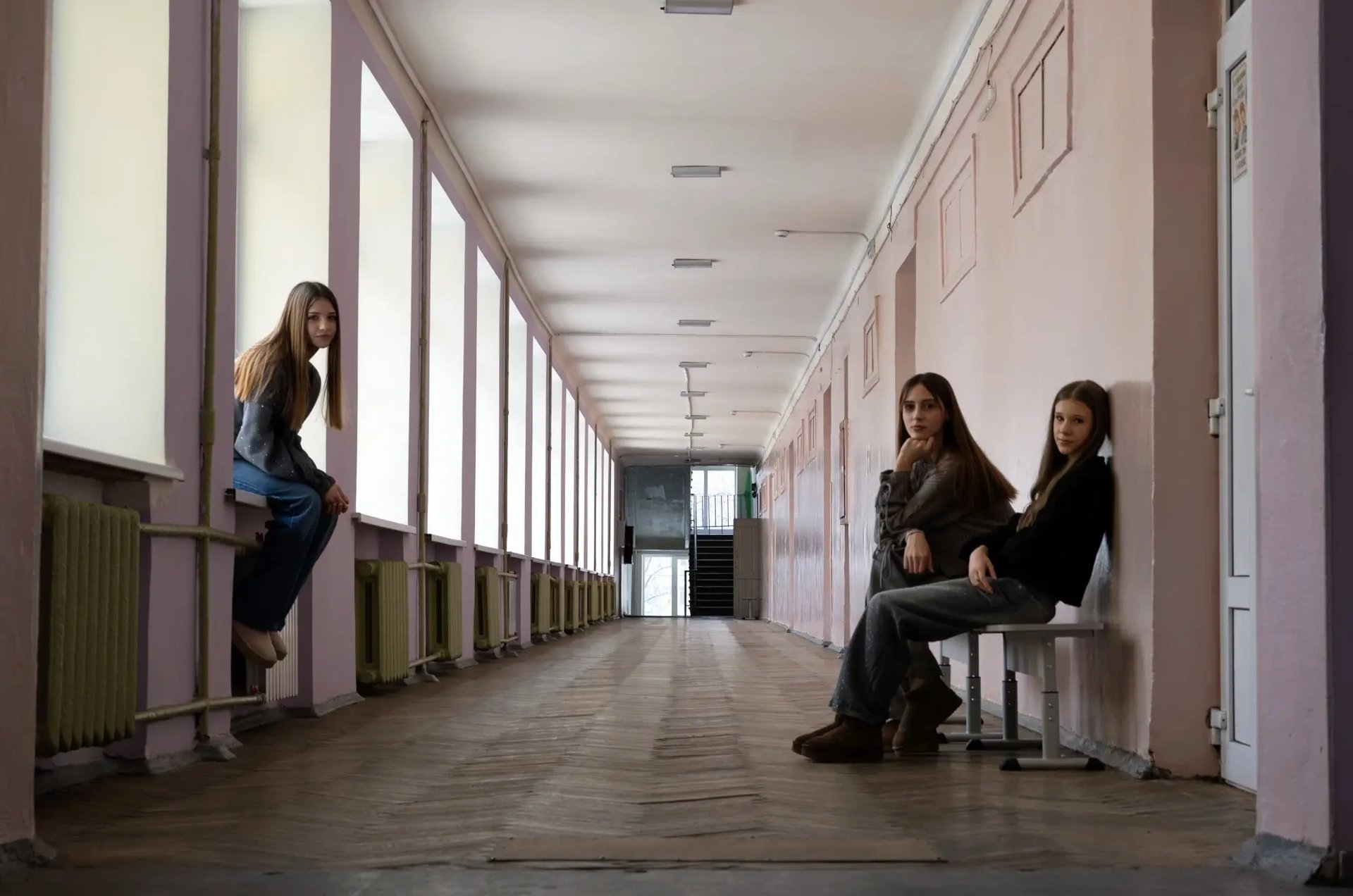 Kateryna, 13 jaar, Kateryna, 14 jaar, en Zoriana, 14 jaar, in de gang van een verlaten school in Oekraïne.