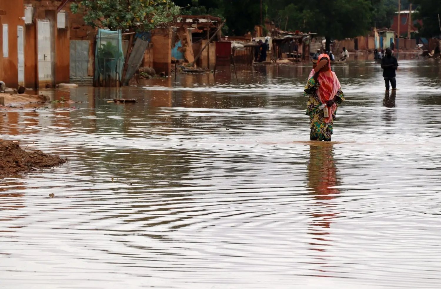 Een jong meisje loopt door de overstroomde straten van haar dorp in Niger