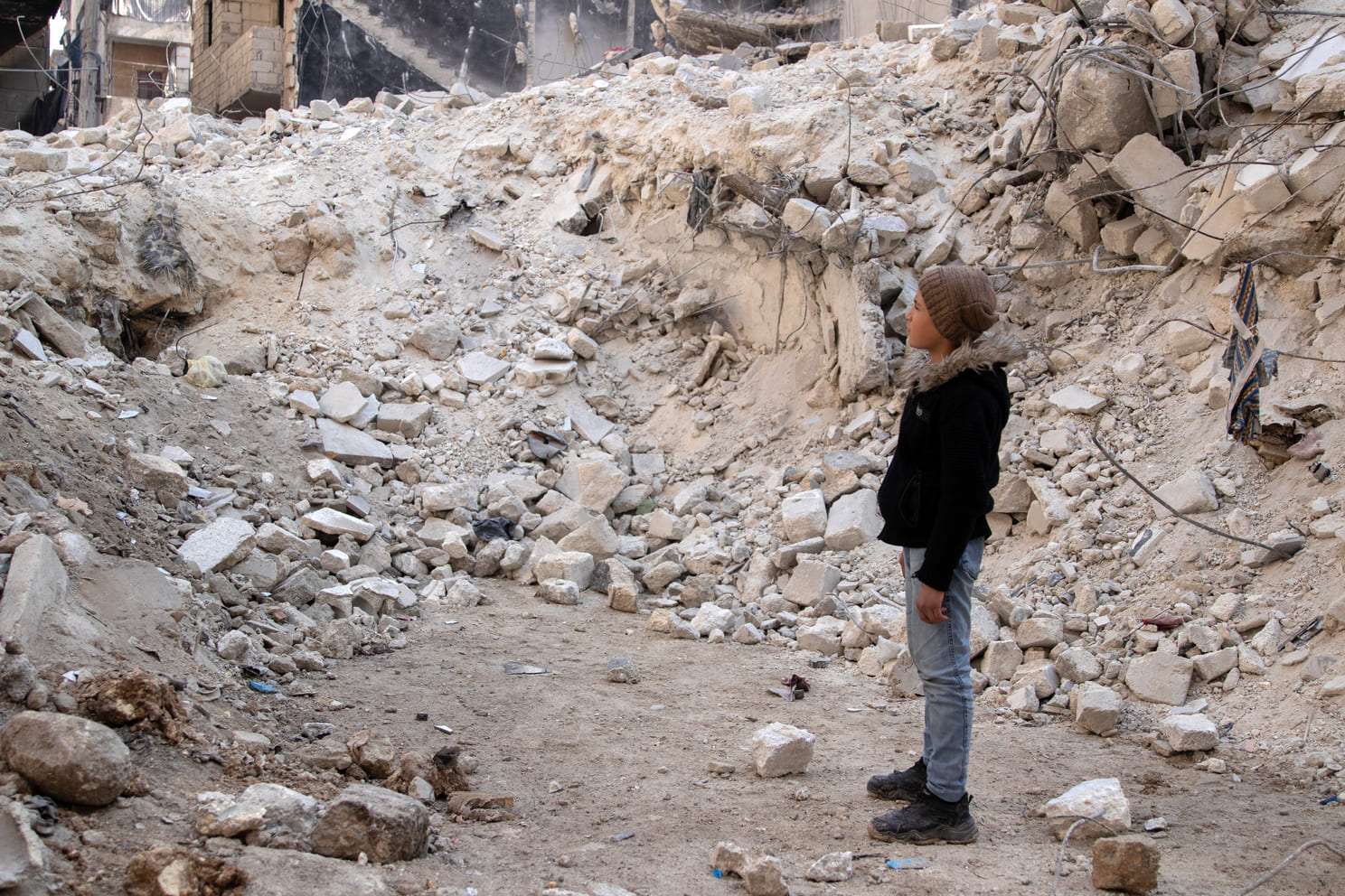 Jongen tussen de ruïnes van de aardbeving in Syrië.