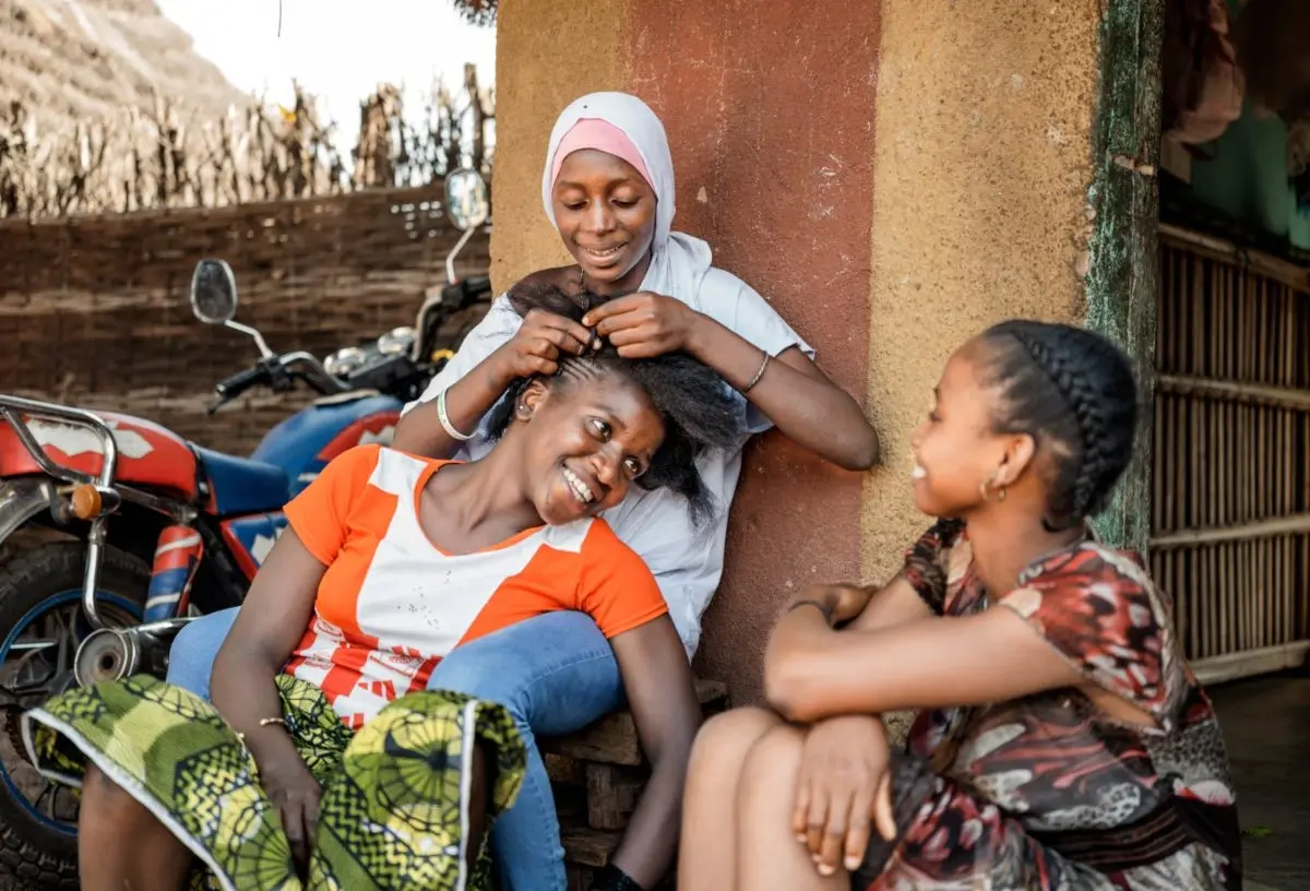 Bevrijd van de last van vrouwelijke genitale verminking vlecht Fatou het haar van haar vriendin Adama.