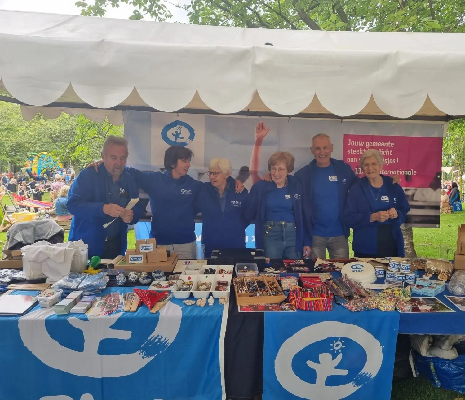 La photo montre six membres du groupe de travail local derrière leur stand bleu à la Fiesta Mondial.