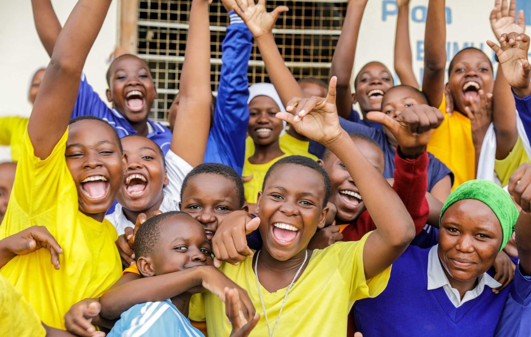 Des enfants et des jeunes sourient à la caméra. 